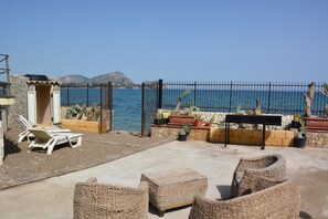 A patio with wicker furniture, a small structure, and a view of the sea. - Villa on the beach whit private beach (Casteldaccia)