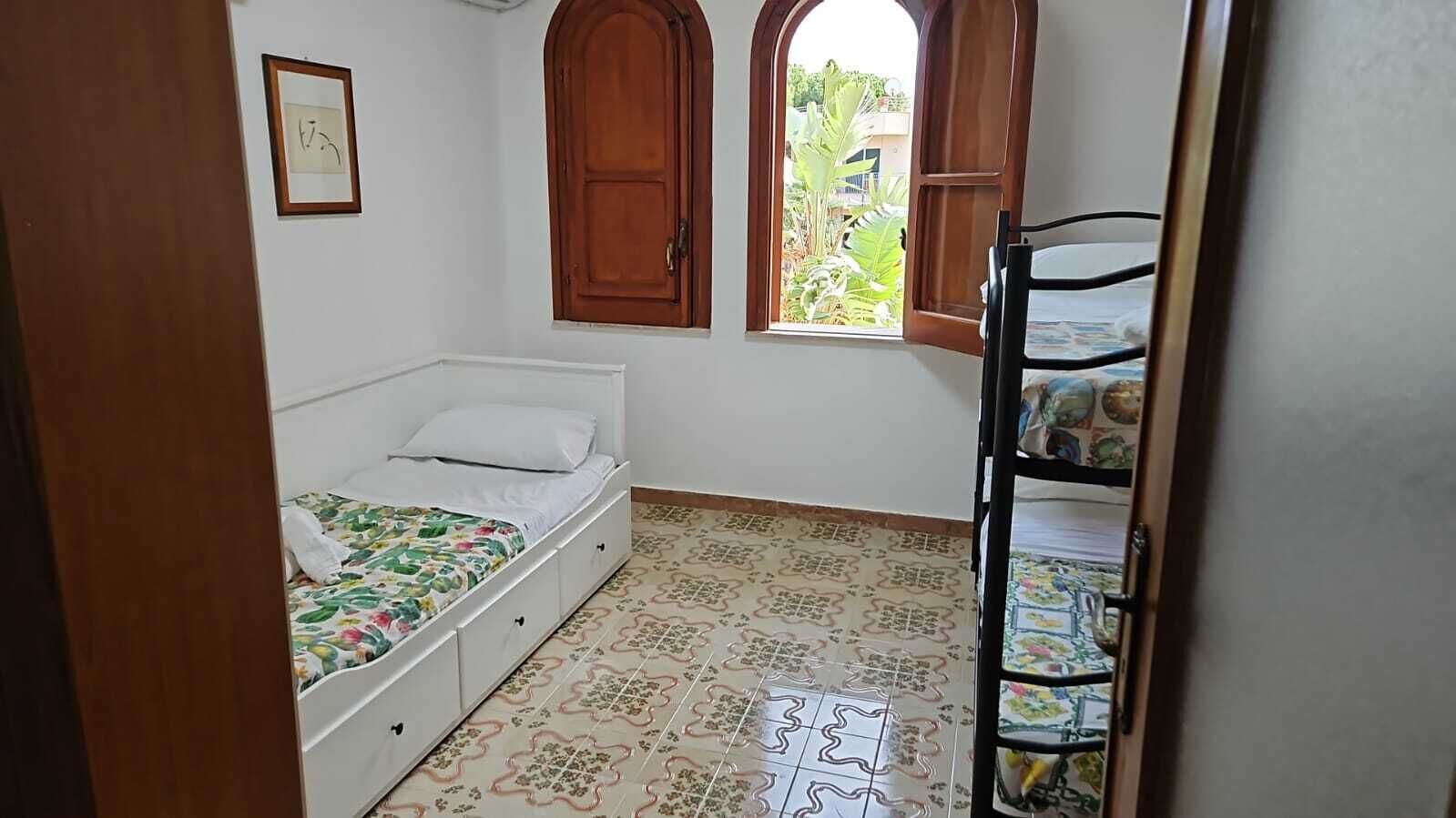 A bedroom with a bed, a window, and a bunk bed.
