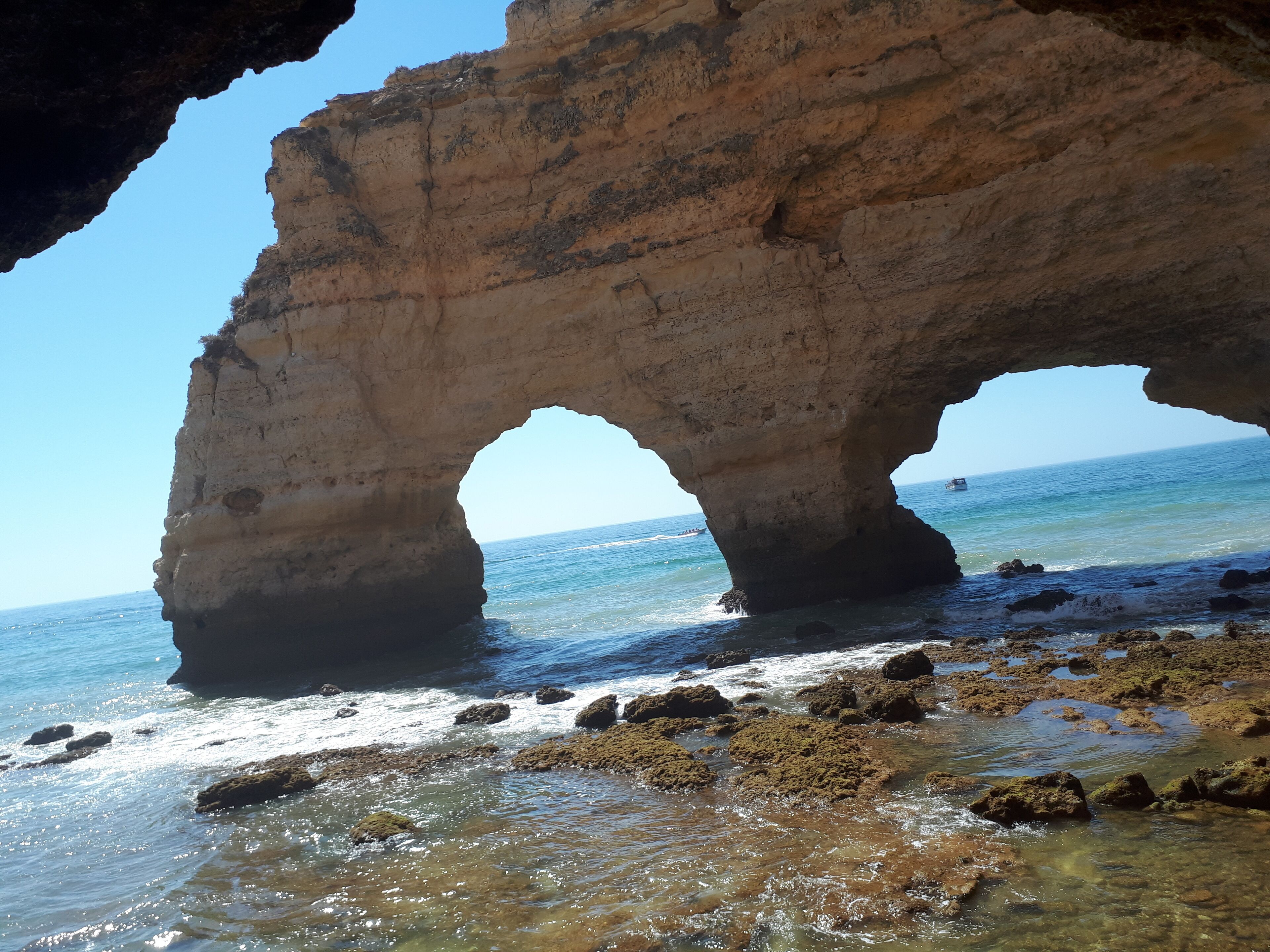 Formación rocosa natural con un arco parecido a una cueva sobre una playa.