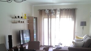 A modern living room with a sofa, a dining table with chairs, a TV, and a chandelier. - Luxury apartment in a private and relaxing complex (Albufeira)