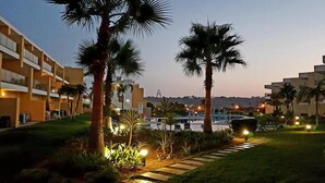A hotel with a pool, palm trees, and a well-lit pathway. - Luxury apartment in a private and relaxing complex (Albufeira)