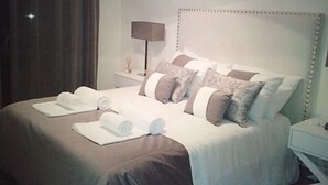 A neatly made bed with a headboard, pillows, and rolled towels. - Luxury apartment in a private and relaxing complex (Albufeira)