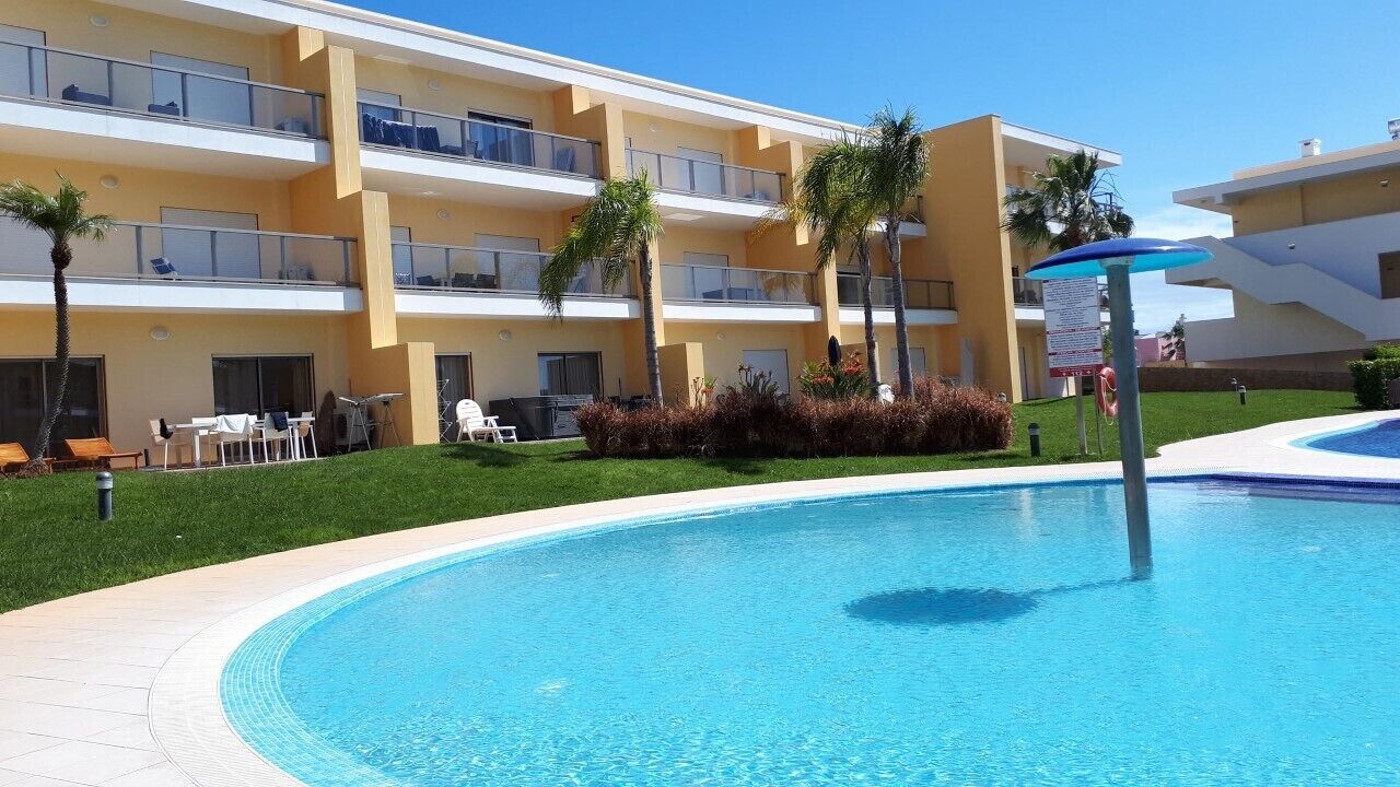 Un hotel con piscina, asientos al aire libre y palmeras.