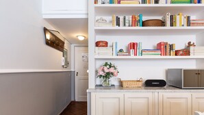 A kitchen with white cabinets, a microwave, a basket, and a vase with flowers. - Paradiso | Romantic open space in the heart of Rome (Roma)