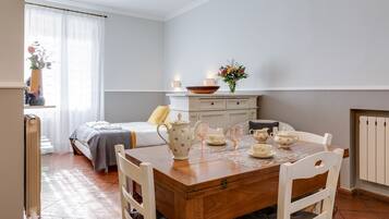 Une chambre confortable avec un lit, une table de chevet et une commode. Une table à manger avec des chaises se trouve au premier plan.