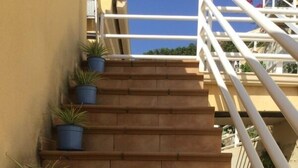 A staircase with potted plants on the steps, leading to a balcony with a railing.