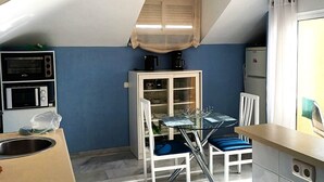 A compact kitchen with a dining area, a microwave, a coffee maker, and a refrigerator.