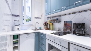 A modern kitchen with white and blue cabinetry, a built-in dishwasher, and a coffee maker.
