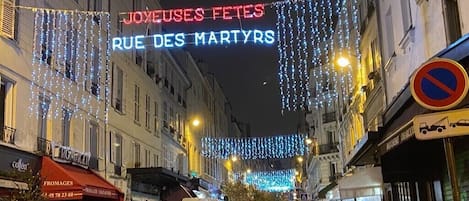 A street with illuminated signs and string lights, indicating a festive atmosphere.