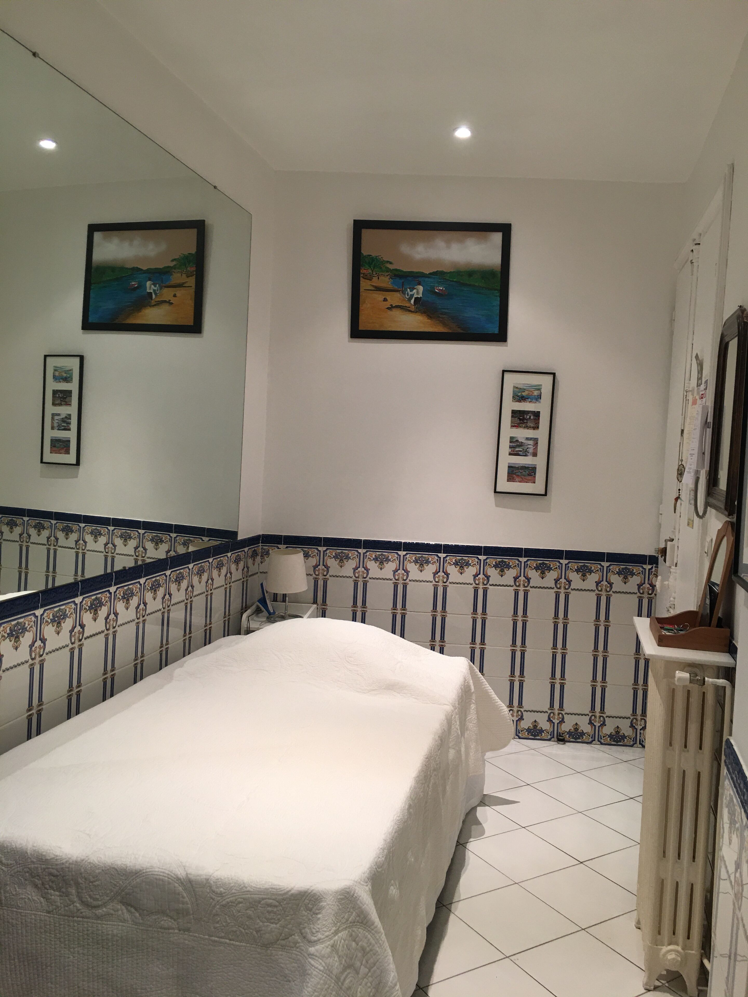 Een slaapkamer met een bed, een grote spiegel en twee foto's in lijsten aan de muur.
