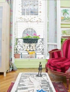 Una habitación con una puerta blanca, un sillón rojo y una pequeña mesa con una estatua.