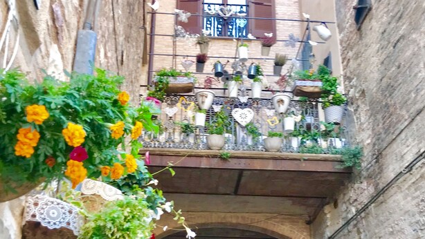 A narrow alleyway with a building on the right featuring a balcony with potted plants and a sign reading "QUIN". - PATIO HOUSE balcony shabby chic home in Spello (Spello)