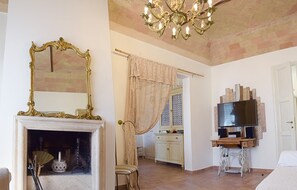A room with a fireplace, a large mirror, a television on a wooden stand, and a chandelier. - PATIO HOUSE balcony shabby chic home in Spello (Spello)