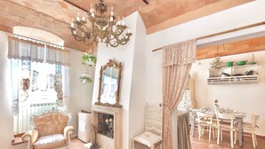 A room with a fireplace, a dining table with chairs, a chandelier, and a large mirror. - PATIO HOUSE balcony shabby chic home in Spello (Spello)