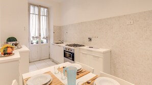 Una cocina compacta con gabinetes blancos, una estufa a gas y una ventana con cortinas.