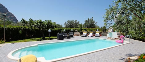 Relax by the serene pool surrounded by lush greenery and comfortable seating options.