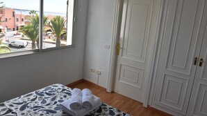 A hotel room with a bed, a window with a view of the street, and a white door. - The Outside Christians, Fantastic Views. (Arona)