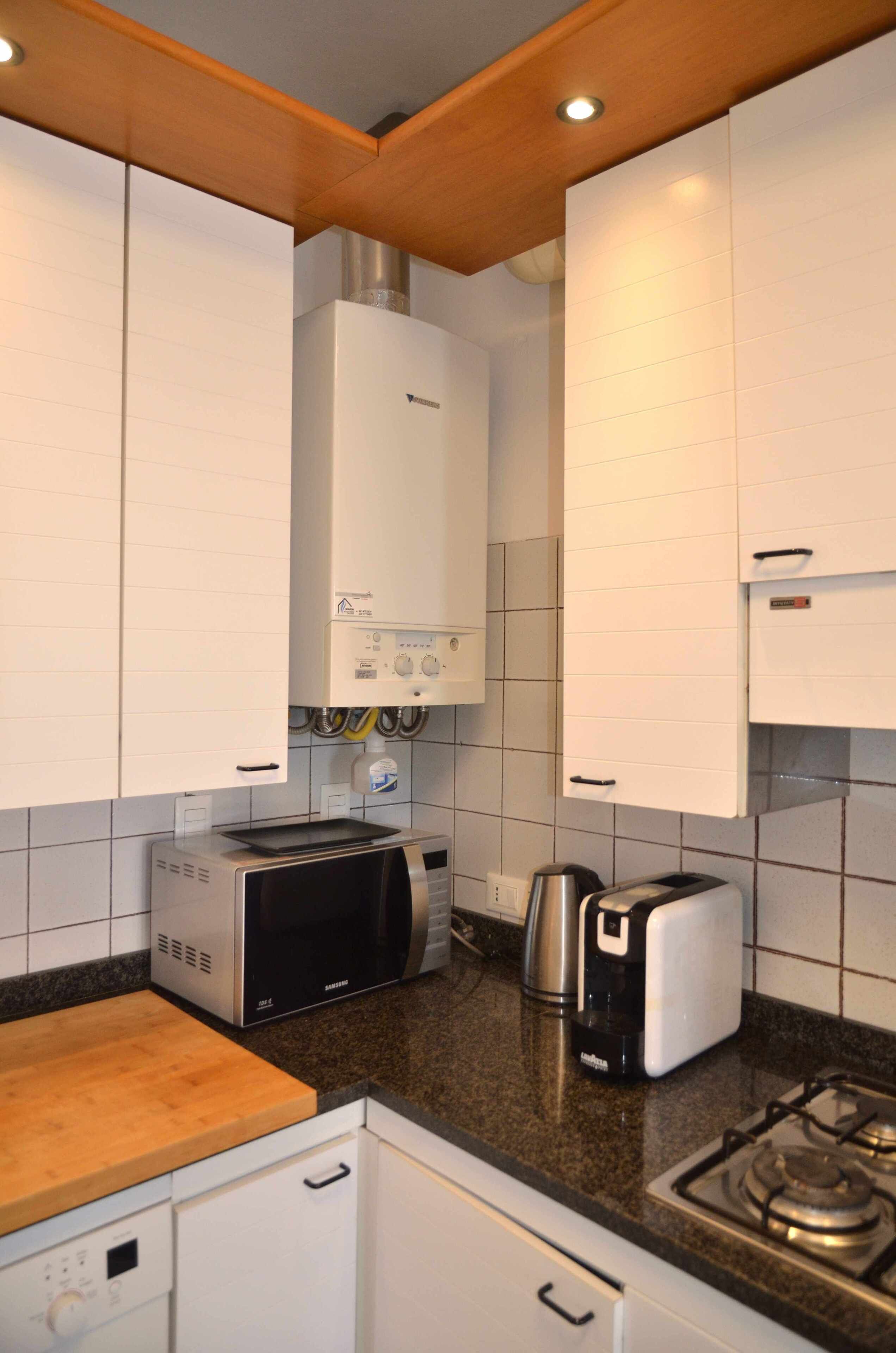 Eine Küche mit weißen Schränken, einer Mikrowelle, einem Toaster, einem Wasserkocher und einem Gasherd.