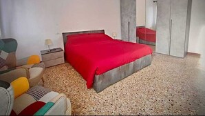 Ein Schlafzimmer mit einem Bett, einem Nachttisch, einem Sessel und einem Kleiderschrank.