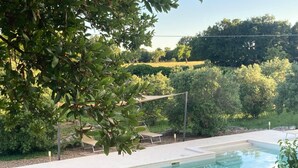 Une piscine rectangulaire à l’eau d’un bleu limpide, entourée d’une terrasse en béton et agrémentée d’une pergola qui offre de l’ombre.