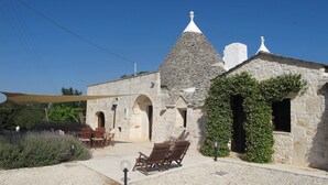Un bâtiment en pierre doté d’un toit conique, d’un espace extérieur aménagé pour s’asseoir et d’une pergola.