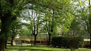 A grassy park area with trees, a bench, and a building in the background. - Exclusive apartment of 120 sqm, 4-6 sleeps, private parking (Milano)