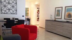 A modern living room with a red armchair, a grey sofa, and a wooden cabinet. - Exclusive apartment of 120 sqm, 4-6 sleeps, private parking (Milano)