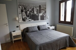 Ein Schlafzimmer mit einem Bett, einem Nachttisch, einem Fenster und einer Heizung.
