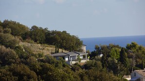 Una casa costera rodeada de árboles con vista al mar.