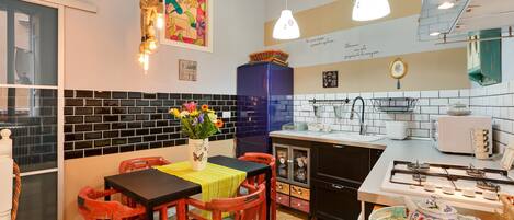 A compact kitchen with a dining area, featuring a black tiled backsplash, a blue cabinet, and a gas stove.