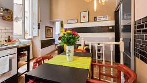 Una cocina acogedora con una mesa de comedor, sillas, un florero con flores y una escalera.