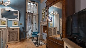 Una habitación con un espejo grande, televisión y una silla azul.