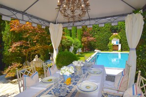 A tented outdoor dining area with a pool in the background. - VILLA FLORENCE LUXURY RELAIS 24H SERVICE PRIVATE CHEF and Breakfast Basket (Camaiore)