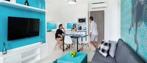 Una sala moderna con un televisor de pantalla plana grande, un sofá gris y una pared de acento color turquesa.