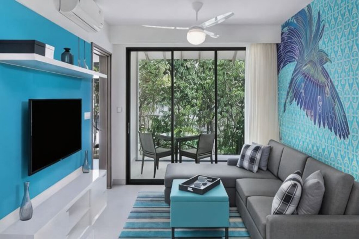 A modern living room with a flat-screen TV, a grey sofa, and a blue accent wall.