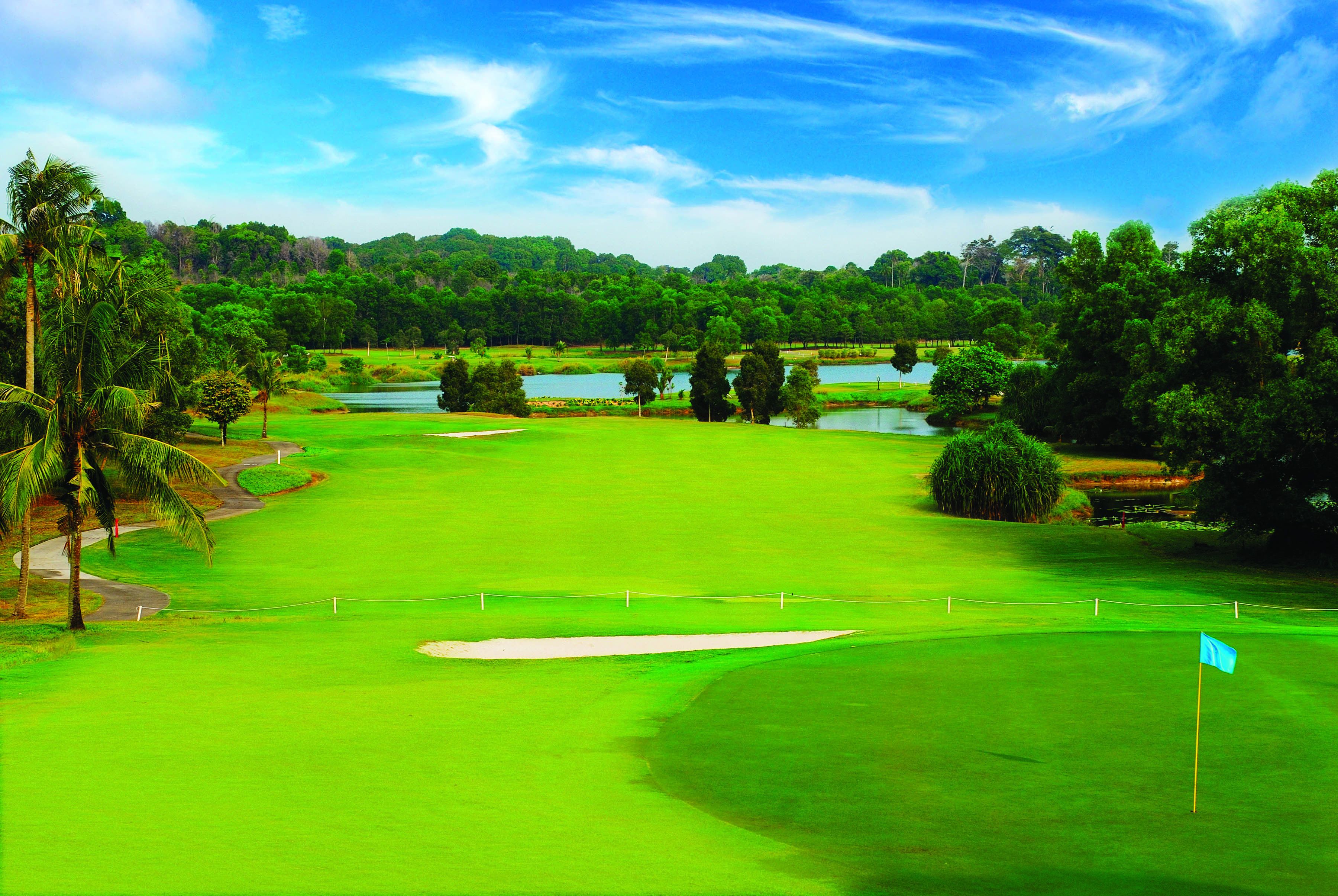 A golf course with a flag, sand bunkers, and a pond.