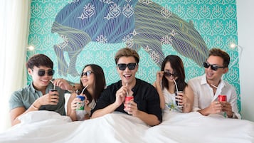 A group of people sitting on a bed with a patterned wall behind them.