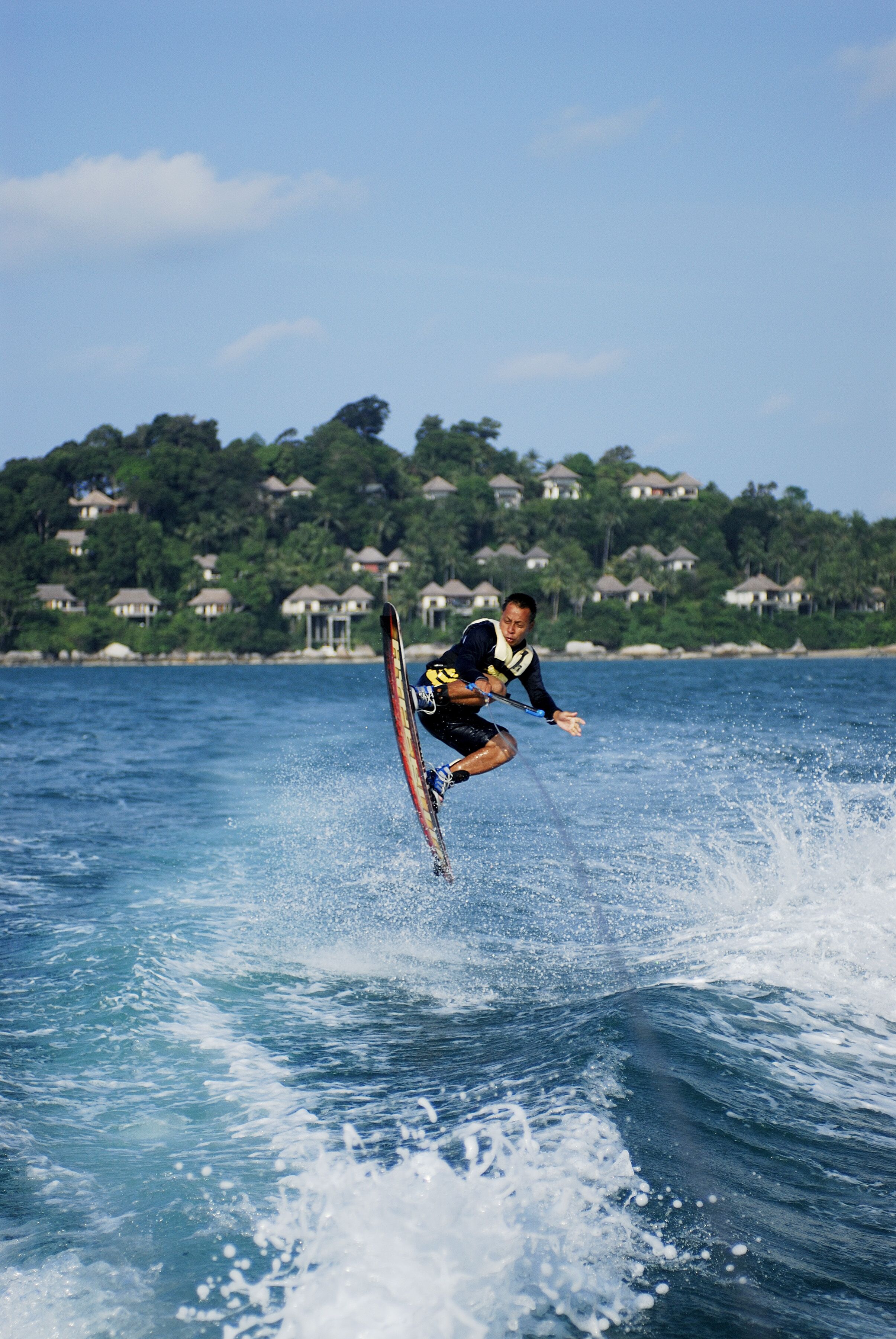 A person wakeboarding on a body of water with houses in the background.