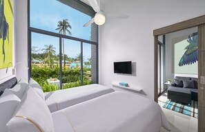 A hotel room with two beds, a TV, and a balcony with a view of palm trees and a pool. - Cassia Bintan, part of Banyan Group (Bintan)