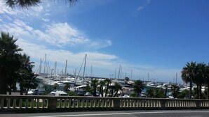 Un port de plaisance où sont amarrés de nombreux bateaux, un ciel dégagé et une route au premier plan.