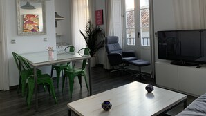 Un salon moderne comprenant un coin repas, un téléviseur et une grande fenêtre agrémentée de rideaux.