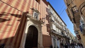 Un bâtiment historique doté d’une grande entrée en arc de cercle, d’une façade ornée et donnant sur une rue piétonne.