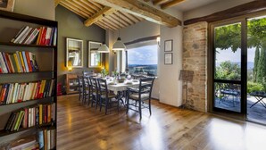 A dining area with a wooden ceiling, bookshelves, and a view through a glass door. - Casale Delle Lavande 10, Emma Villas (Todi)