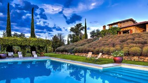 A swimming pool with lounge chairs, a stone house with a red roof, and a hillside garden. - Casale Delle Lavande 10, Emma Villas (Todi)