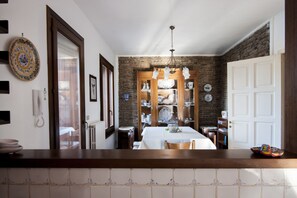 Enjoy dining in this charming space with a brick wall, wooden cabinetry, and a chandelier.
