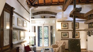 A rustic room with a wooden ceiling, a sofa, a chair, a table, and a door with a lattice design.