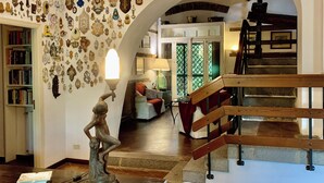 A spacious living area with a red sofa, a statue, and a staircase leading to an upper level.