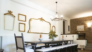 A dining area with a long table, benches, chairs, and a chandelier.