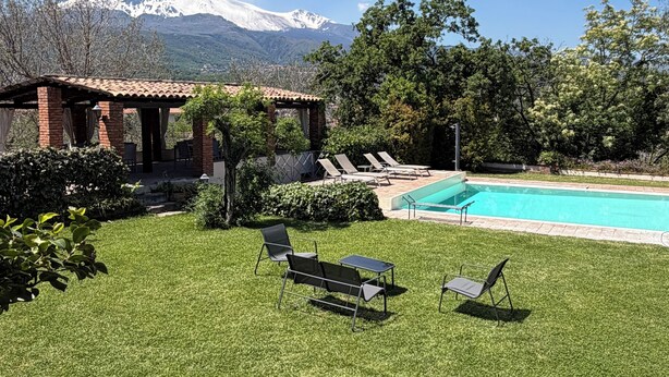 A backyard with a pool, lounge chairs, and a mountain view.