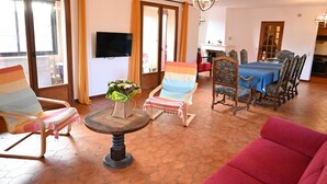 A living room with a sofa, chairs, a table, and a TV.